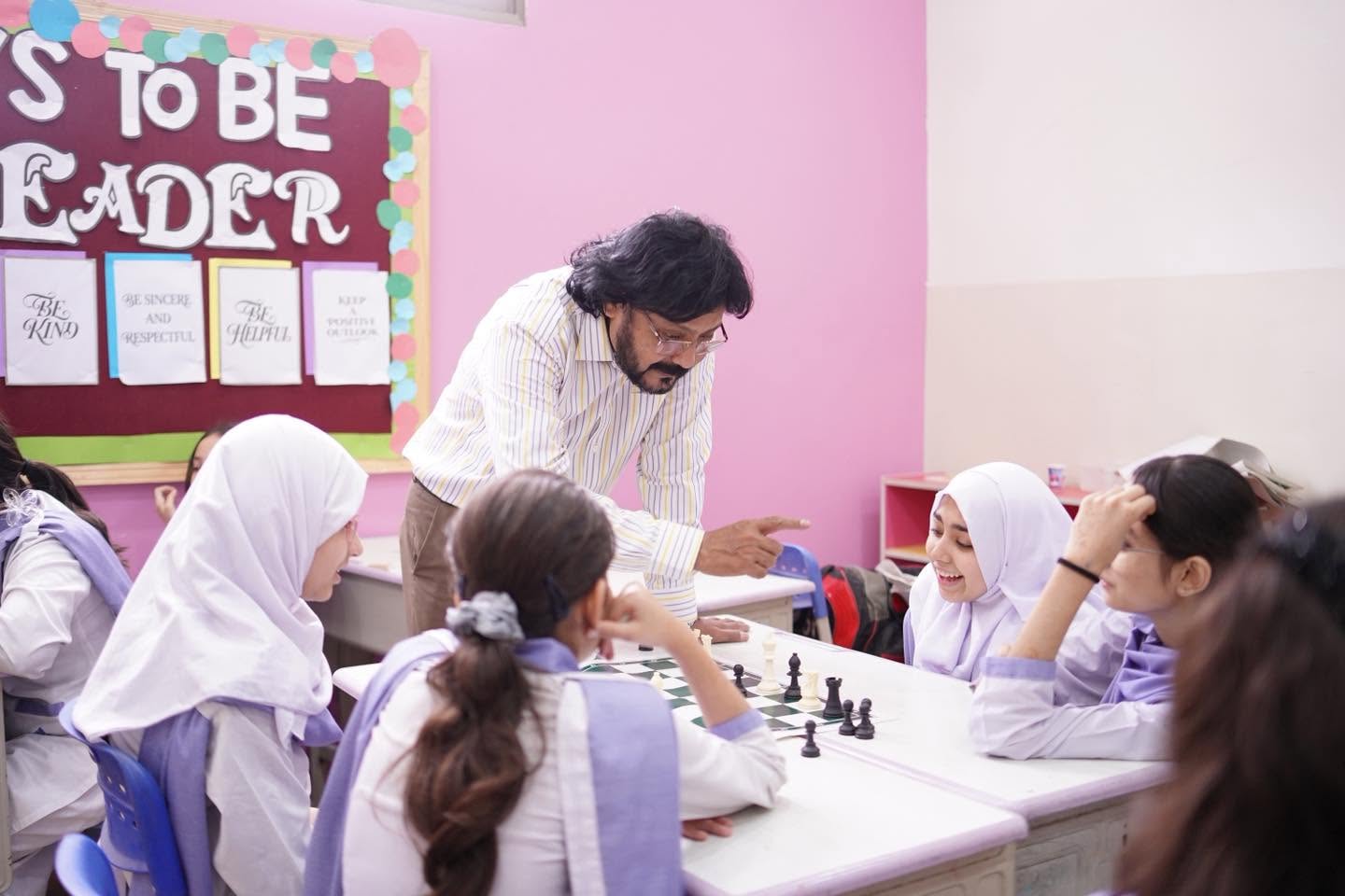 An instructor guiding HPGS students through a chess position