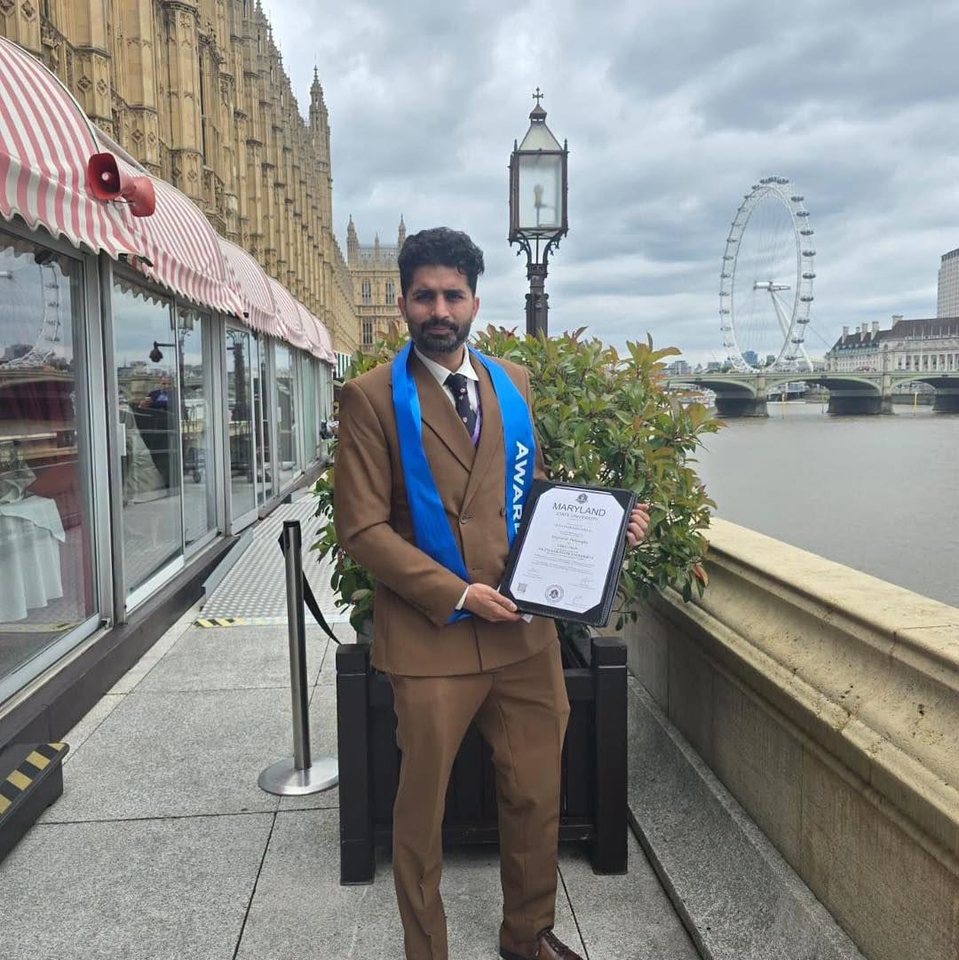 Mr Muhammad Hassan Khan holding his honorary doctorate certificate beside the Palace of Westminster and London Eye