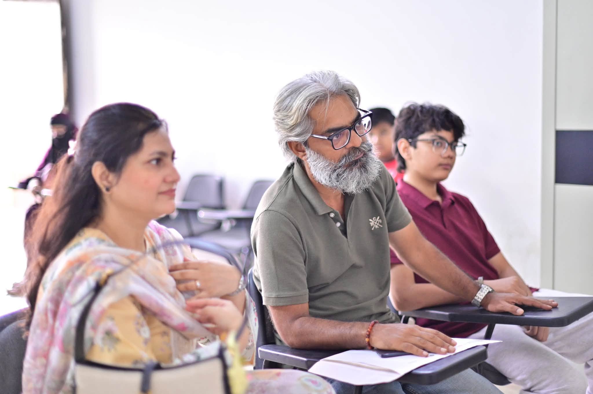 Parents and a student listening attentively during an HPGS orientation meeting