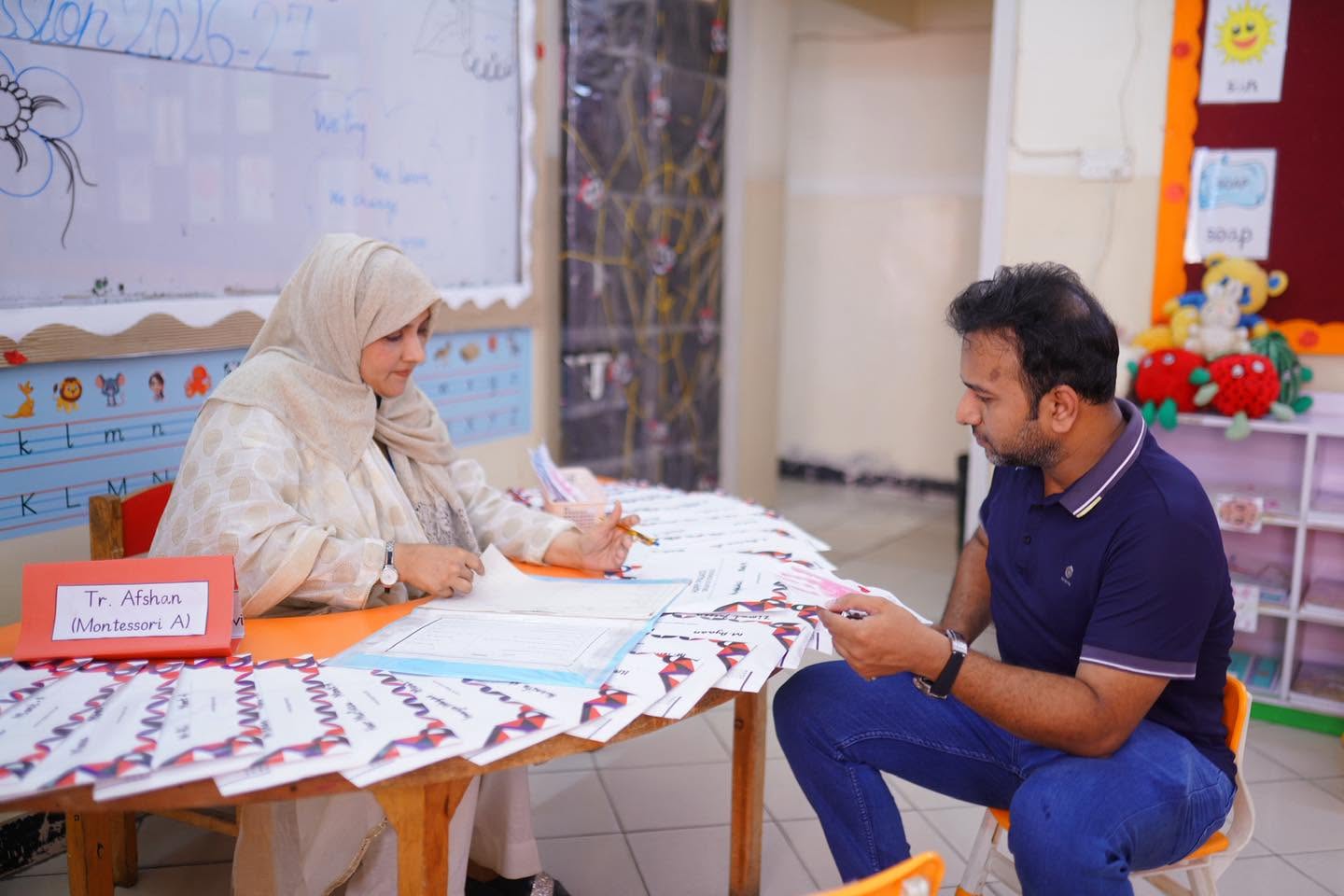A teacher and parent reviewing a student portfolio during an HPGS parent–teacher meeting
