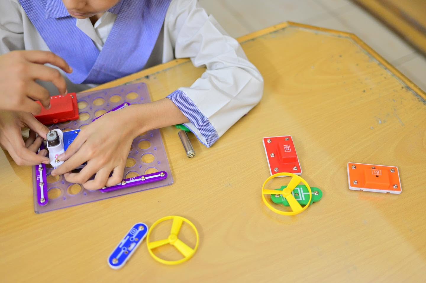 An HPGS learner assembling components on a foundational electronics board